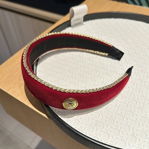 Detail of red velvet headband with gold chain trim and vintage coin button emblem
