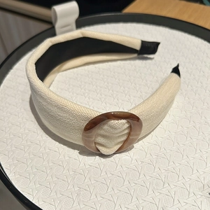 Detail of cream fabric headband featuring a retro brown tortoiseshell ring decoration