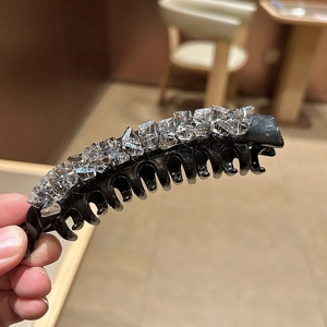 Dettaglio di un fermaglio per capelli a banana nero con cristalli lucidi in mano