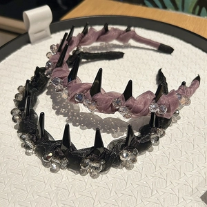 Dettaglio di cerchietti eleganti in seta nera e viola con strass e borchie punk
