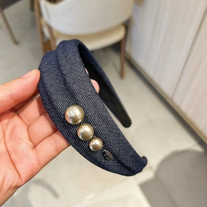 Gros plan détaillé d'un serre-tête en denim bleu avec perles élégantes et logo métallique