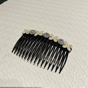 Gros plan sur un peigne à cheveux noir élégant avec trèfle à quatre feuilles et perles