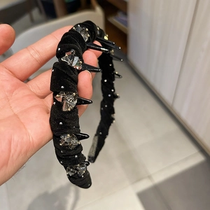 Detail of black velvet headband with sparkling rhinestones and edgy studded spikes