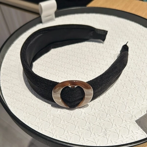 Close-up of black fabric headband with vintage amber resin heart buckle on display