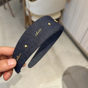 Detail of blue denim headband with gold rivets and metallic Aivai logo for women