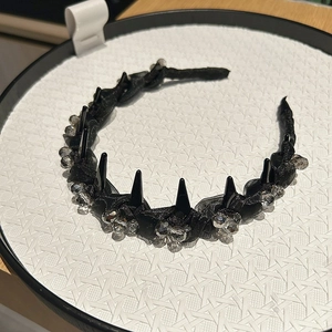 Dettaglio del cerchietto punk nero con punte metalliche e perline di cristallo luccicanti