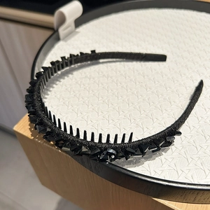 Close-up of black rhinestone headband featuring anti-slip teeth on a display tray