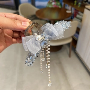 Detailed close-up of a blue mesh bow hair claw clip with dangling crystals and pearl