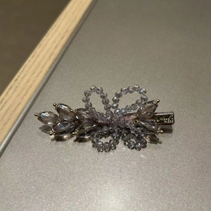 Detail shot of purple crystal floral hair clip showing intricate beadwork and gold metal base
