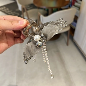Detail of grey mesh bow hair claw clip with hanging pearl tassels and crystal accents