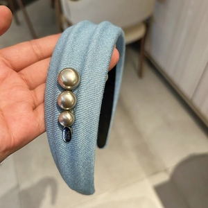 Détail d'un serre-tête en denim bleu clair avec perles champagne et étiquette Hand Made