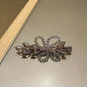 Detailed macro of crystal bead bow hair clip with smoky purple finish and golden clasp