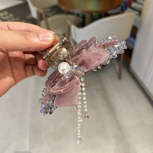 Macro detail of purple mesh bow hair claw clip with faux pearls and crystal tassels