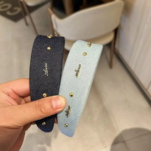 Detail of blue denim headbands with gold studs and metal logo lettering detail
