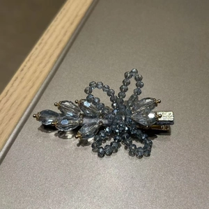 Detail view of handmade blue crystal flower hair clip with satin edges and metal spring