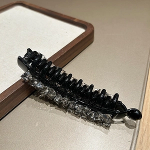 Dettaglio di un fermaglio per capelli a banana nero con file di cristalli quadrati