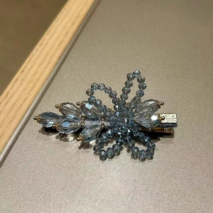 Close-up of a blue-grey crystal flower hair clip with a metallic spring duckbill clasp