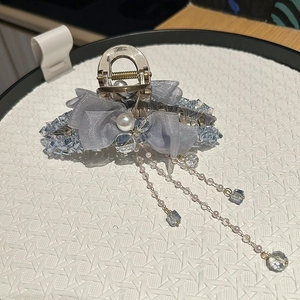 Detail of grey mesh bow hair claw with blue crystals, pearls and hanging tassels