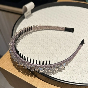 Detail of a thin sparkling rhinestone headband with non-slip teeth on a white tray