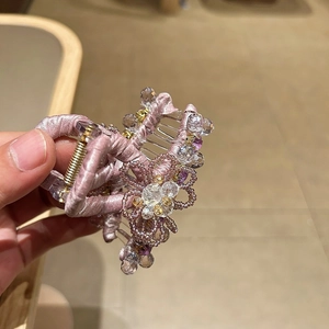 Close-up of pink satin flower hair claw with crystal beads and gold metal spring