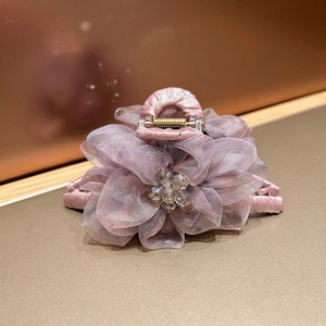 Détail de la pince à cheveux fleur en organza avec cœur en cristal et base en satin