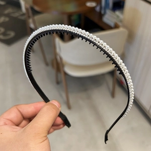 Gros plan sur un serre-tête noir avec perles blanches et strass brillants détaillés