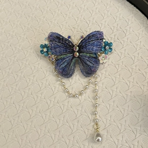 Detail einer bestickten blauen Schmetterlings-Haarklammer mit Perlenquasten und Kristallen