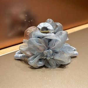 Détail macro d'une pince à cheveux fleur en organza bleu avec perle cristal et fini satin