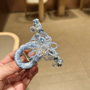 Detail of blue bead-woven floral hair claw with crystals on a silk satin base