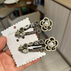 Close-up of vintage black camellia hair clip with pearls, rhinestones and bee charms