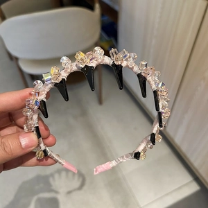 Détail d'un serre-tête en cristal gris clair avec satin rose et détails noirs