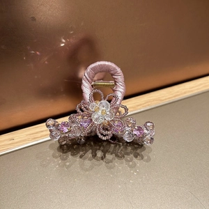 Close-up of pink crystal flower hair claw clip with handcrafted bead and satin detail