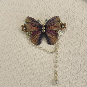 Detail einer bestickten Schmetterling-Haarklammer mit Pailletten und Perlen-Quastenanhänger