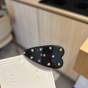 Pince à cheveux cœur noir élégante avec strass colorés sur une carte blanche