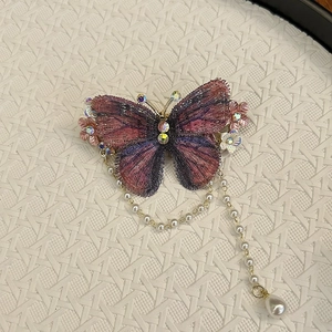 Nahaufnahme von Schmetterling-Haarspange mit bunten Kristallen und Perlenquasten-Detail