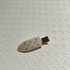 Detail of cream white hair clip with colorful rhinestones on a gold metal base