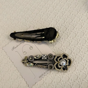 Retro black camellia hair clips with pearls and rhinestones on a textured background