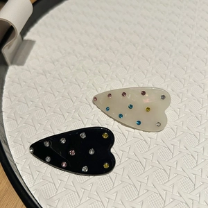 Détail de pinces à cheveux en forme de cœur avec strass colorés en crème et noir