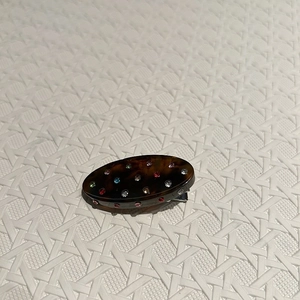 Detail of tortoise shell hair clip with colorful rhinestones on white texture