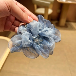 Détail d'une pince à cheveux fleur en organza bleu avec cristaux et bords pailletés