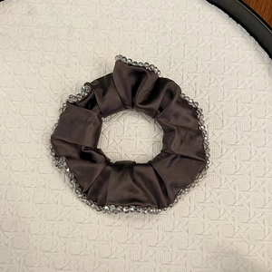 Macro shot of dark brown satin scrunchie with detailed greyish translucent bead edges