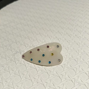 Détail de la pince à cheveux bec de canard blanc crème ornée de petits strass colorés