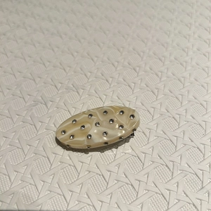 Detail of oval hair clip featuring marble texture acetate and sparkling rhinestones