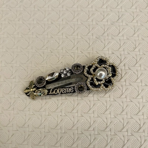 Detail of vintage camellia hair clip with black enamel flower, pearls and golden bee