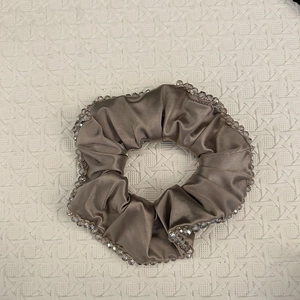 Detailed close-up of champagne satin scrunchie with sparkling hand-sewn crystal beads edge