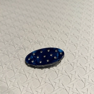 Macro view of oval hair clip with blue marble texture and inset crystal rhinestones