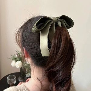 Close-up of olive green knitted bow hair clip on ponytail with soft satin texture