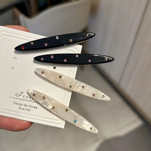 Dettaglio di fermagli per capelli in acetato con strass colorati e motivi marmorei