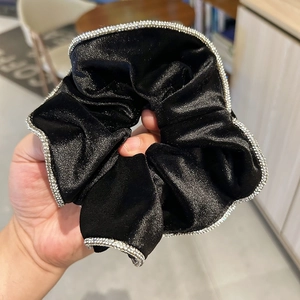 Detailed close-up of a premium black velvet scrunchie with sparkling silver rhinestone trim