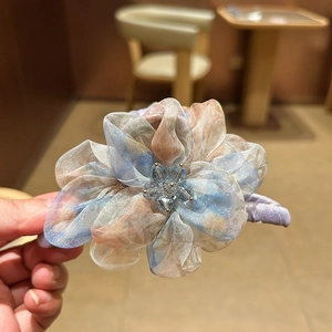Détail d'une pince à cheveux en organza avec fleur et cristal étincelant au centre décor